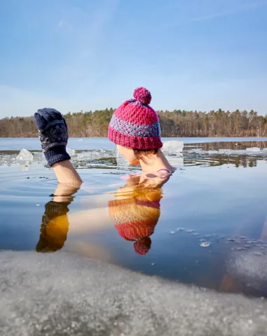 girl in hat and gloves in icy lake