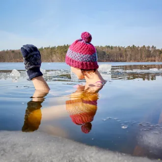 girl in hat and gloves in icy lake