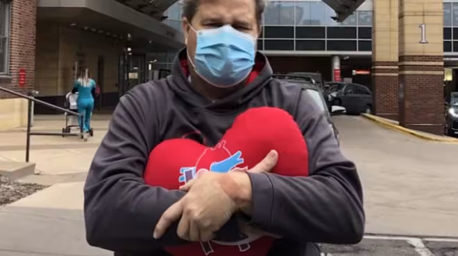 Paul David after surgery holding heart pillow