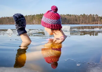 girl in hat and gloves in icy lake