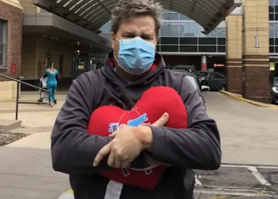 Paul David after surgery holding heart pillow